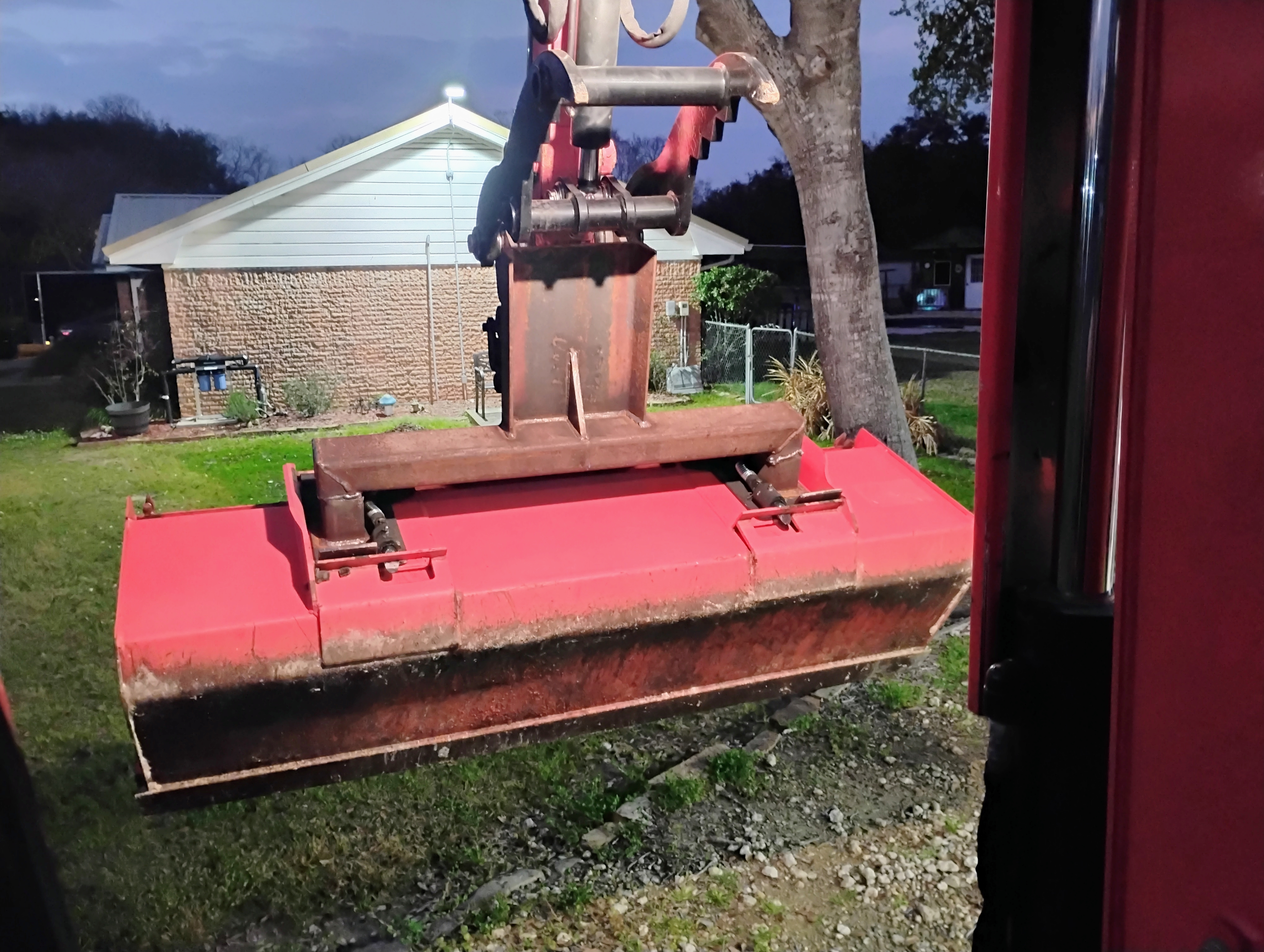 Front view of painted custom brush cutter attachment mounted on mini excavator