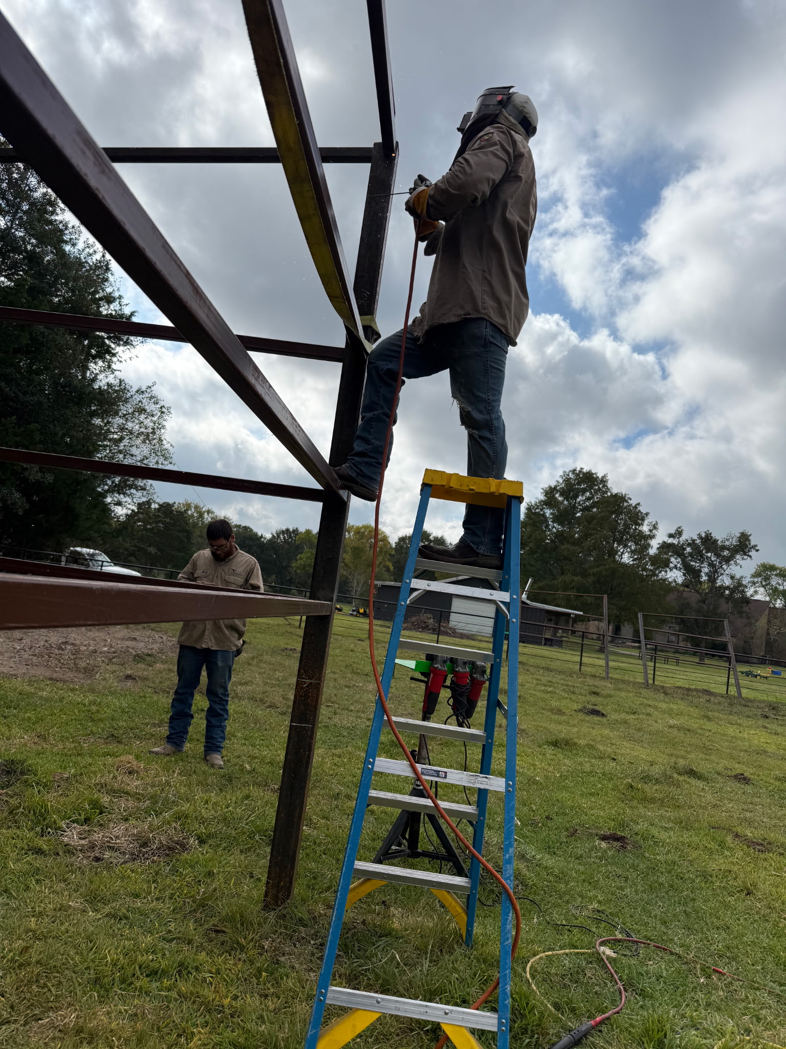Welding team working on ladder